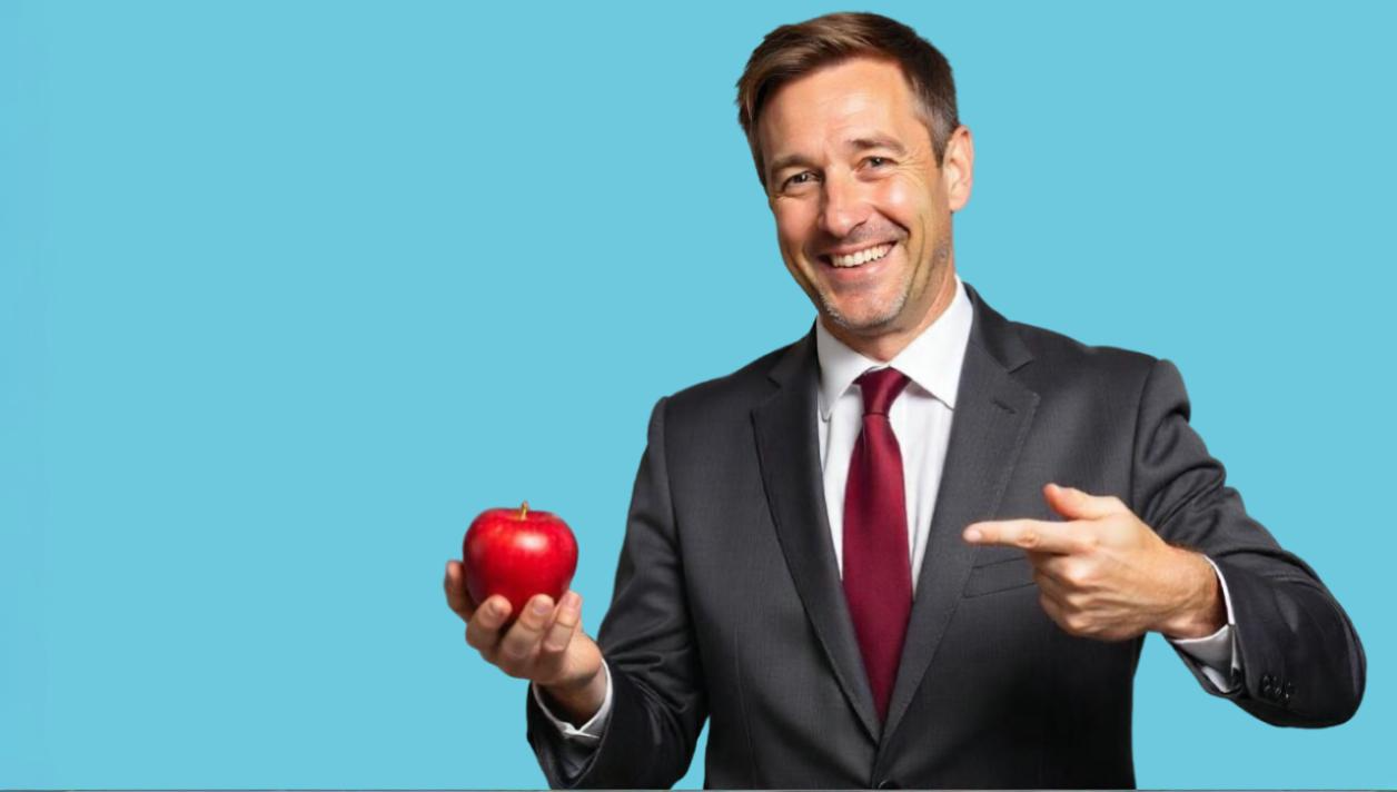 A smiling businessman in a suit holds a red apple and points at it against a solid blue background. The apple, symbolizing knowledge and smart business strategies, highlights the importance of adopting Omnichannel Solutions to enhance Customer Communication Platforms for better engagement.