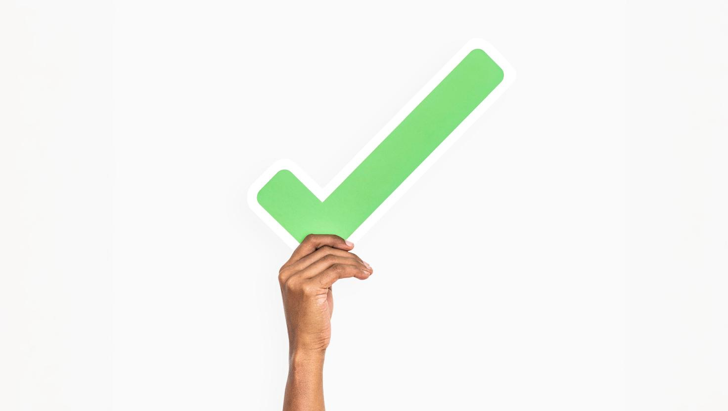 Hand holding a large green checkmark conveying that a good VoIP Provider handles security from international calls to everyday calls on mobile devices.